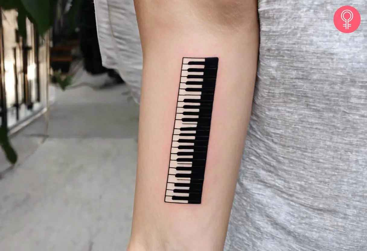 A piano keyboard tattoo on the forearm of a woman