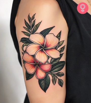 A woman with a vibrant frangipani flower tattoo on her upper arm