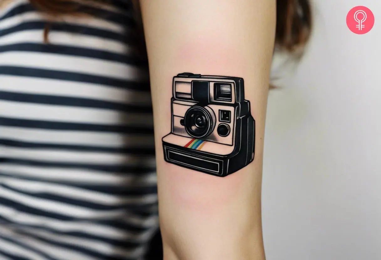 Polaroid camera tattoo on the upper arm of a woman