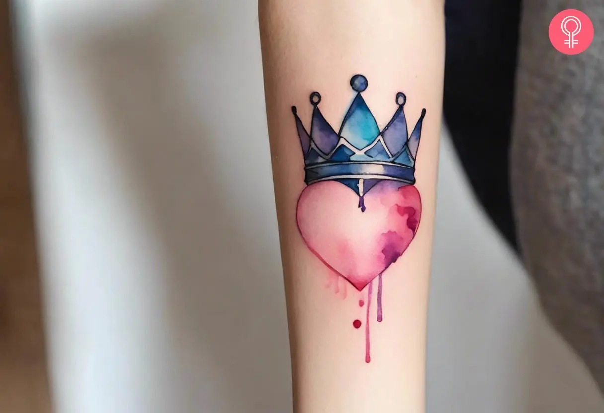 A traditional watercolor crown tattoo on the arm with a heart