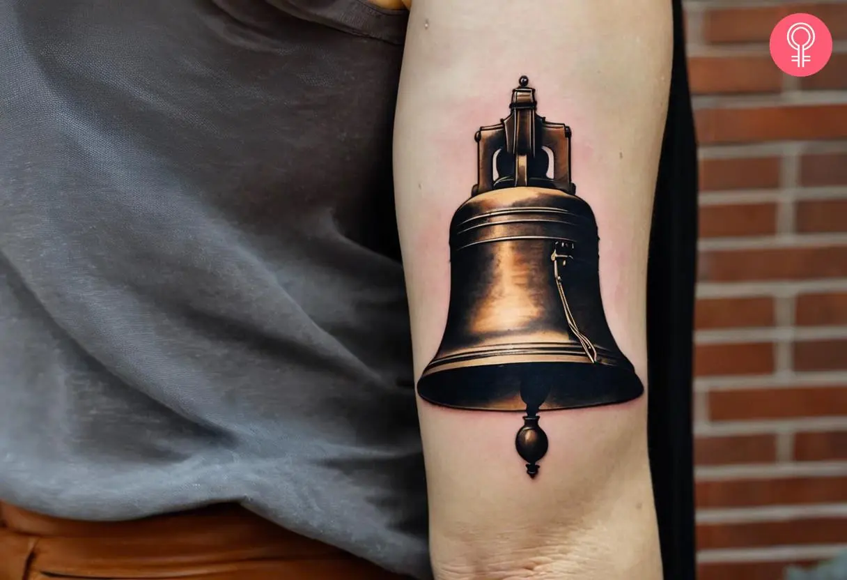 Realistic liberty bell tattoo on the upper arm of a woman