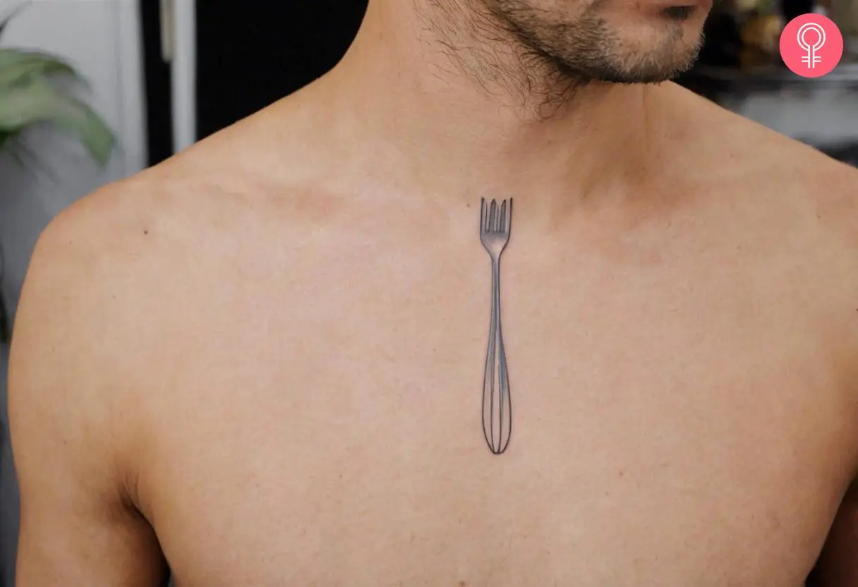 A man wearing a silver fork outline tattoo on the chest.