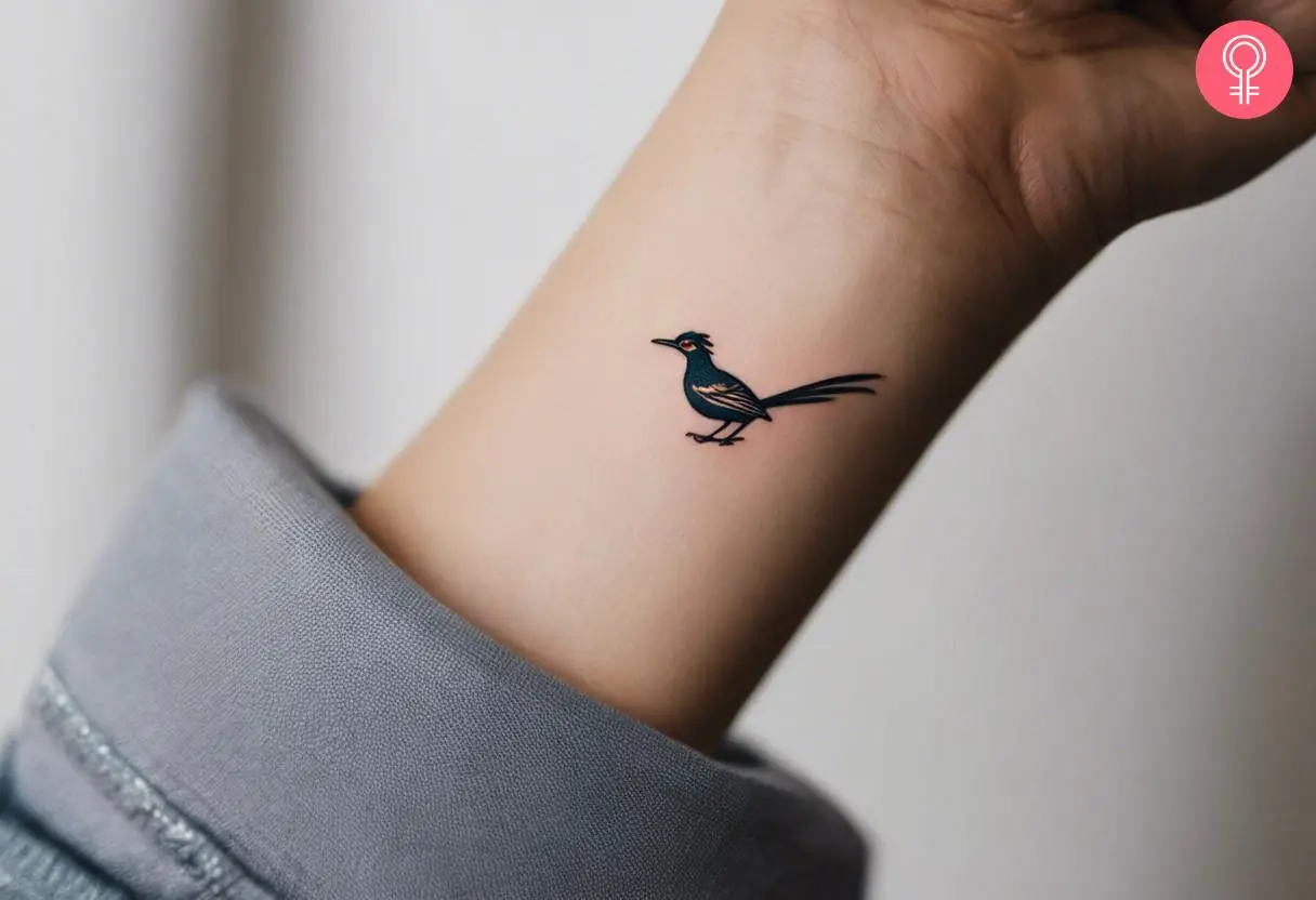 A woman wearing a small roadrunner tattoo on the inner wrist.