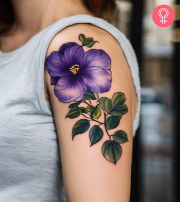 A woman wearing a violet flower tattoo on her upper arm