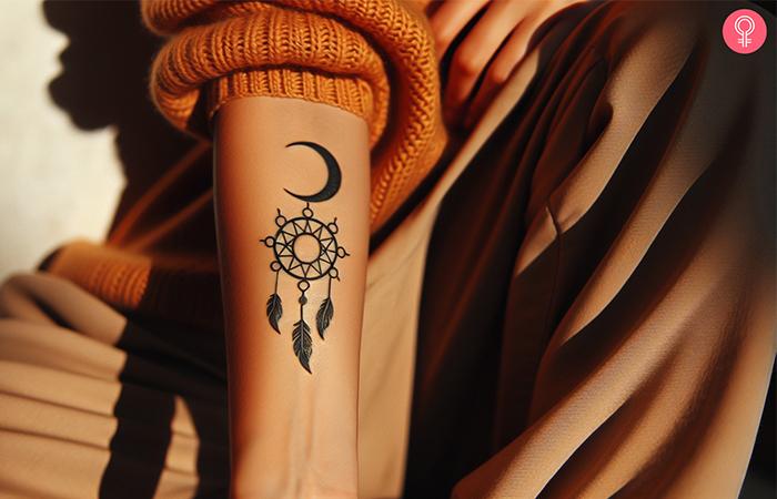 Dreamcatcher tattoo in the shape of a sun and moon on the forearm