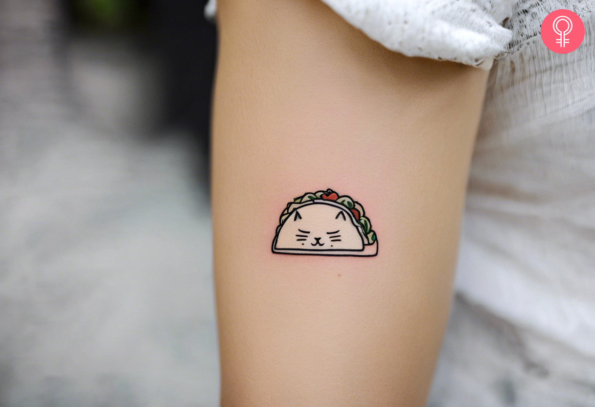 A tiny cute taco cat tattoo on the upper arm of a woman