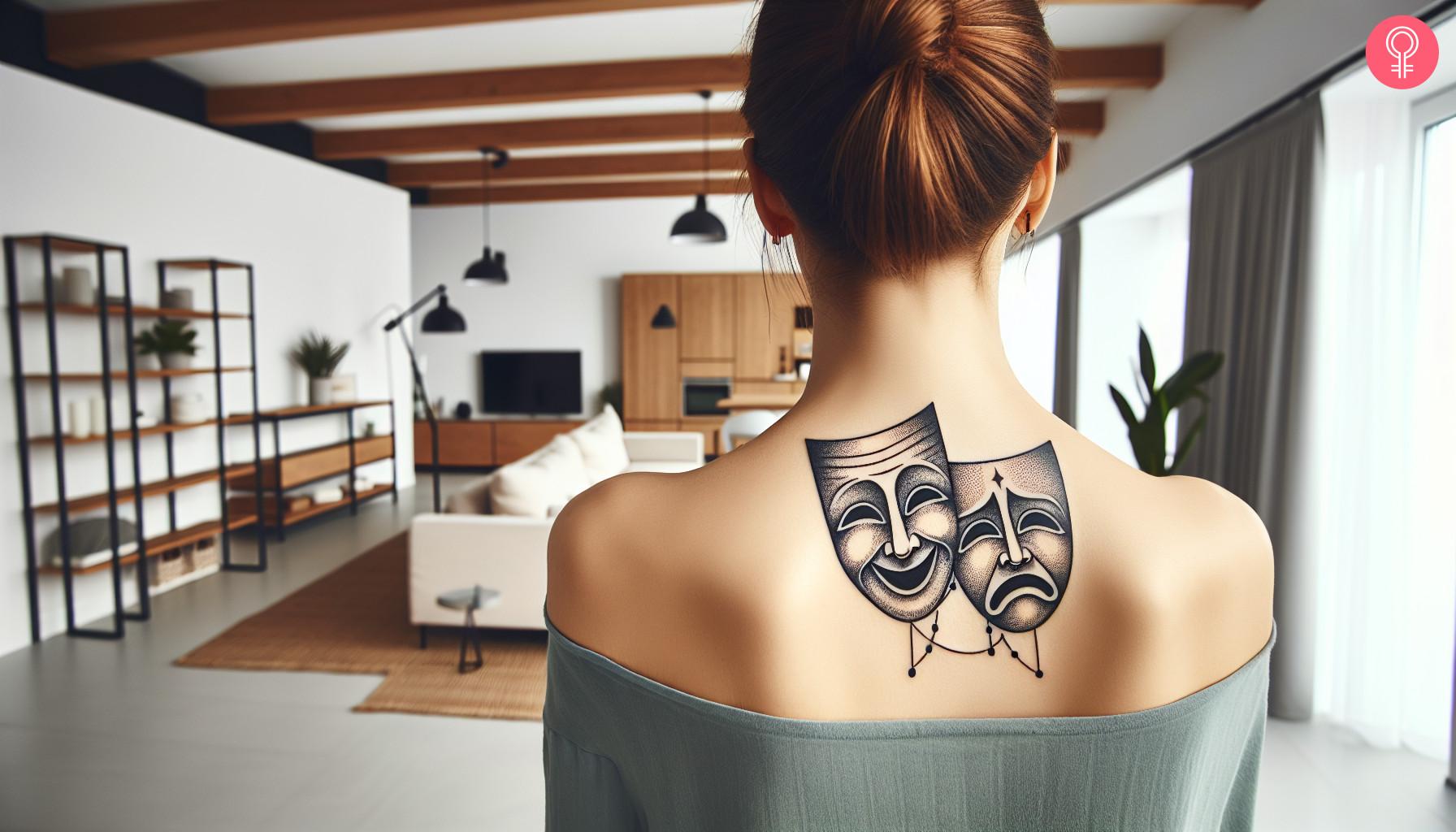 Theater mask tattoo on back