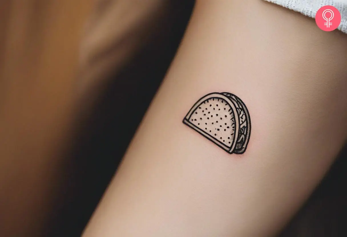 A tiny taco outline tattoo on the forearm of a woman