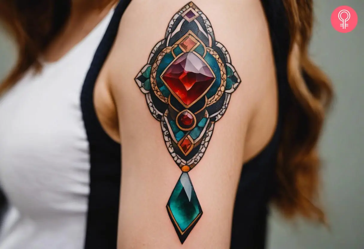 A traditional style gemstone tattoo with ruby and emerald on the upper arm of a woman