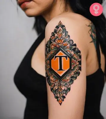 A woman wearing a ‘T’ style letter tattoo on the upper arm.