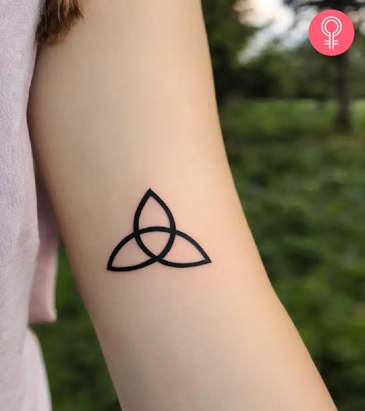 A woman sporting a trinity knot tattoo on the upper arm