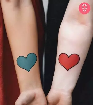 A cross tattoo on the wrists of two sisters