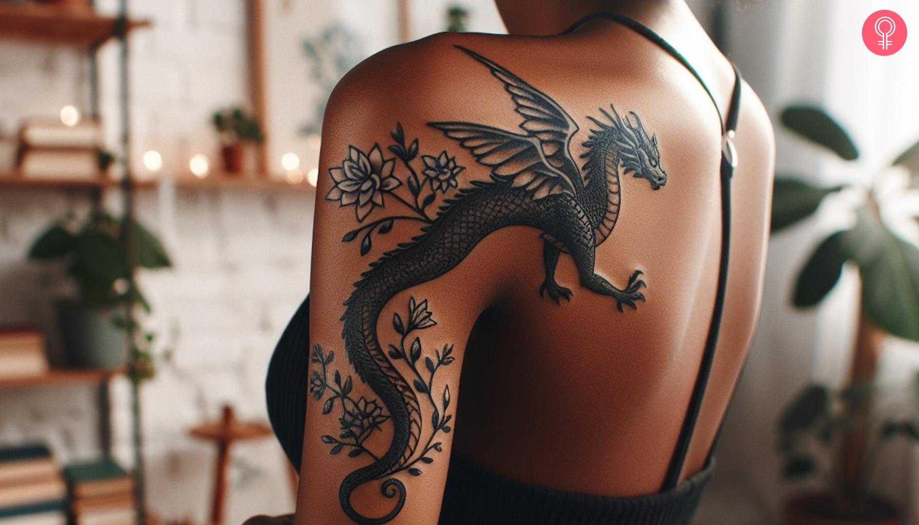 Playful dragon with flowers tattoo on the back of the shoulder