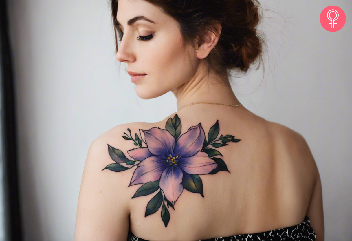 Woman with a larkspur July birth flower tattoo on her back