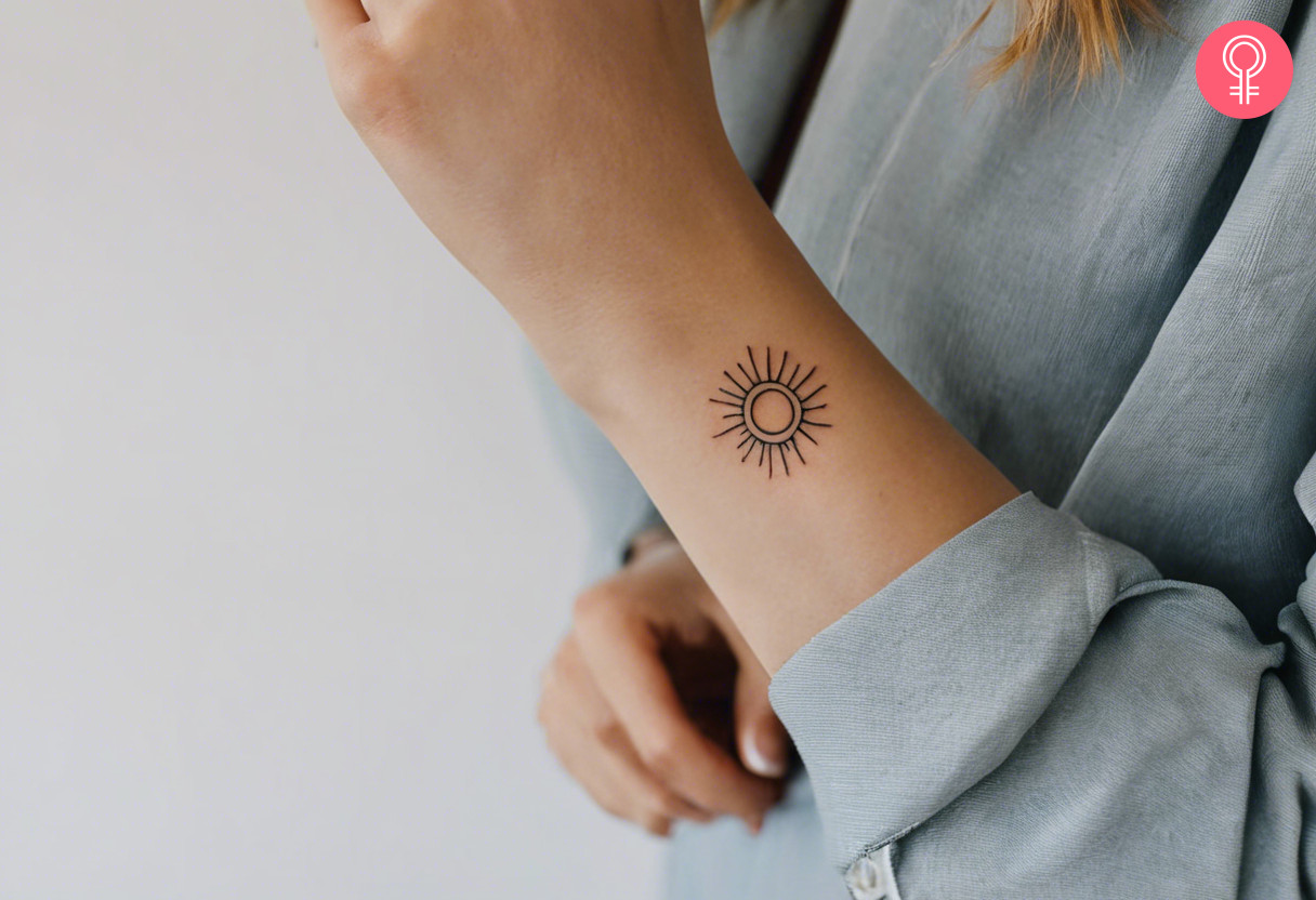 Woman with minimalist sun tattoo on her wrist