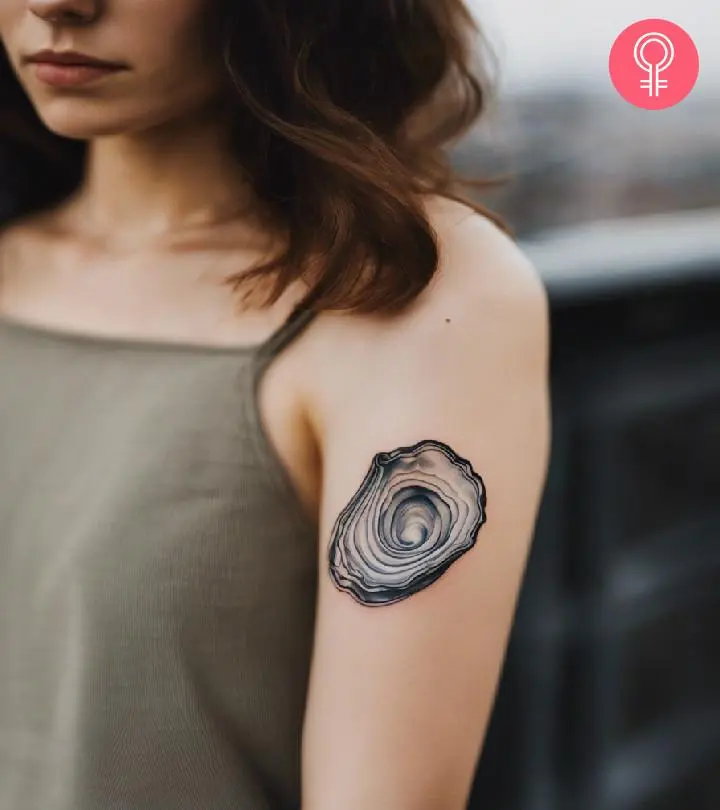 A woman with a simple oyster tattoo on her upper arm