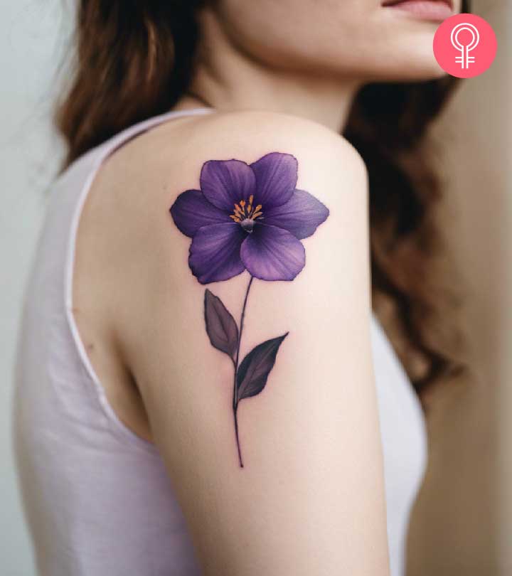 A woman wearing a violet flower tattoo on her upper arm