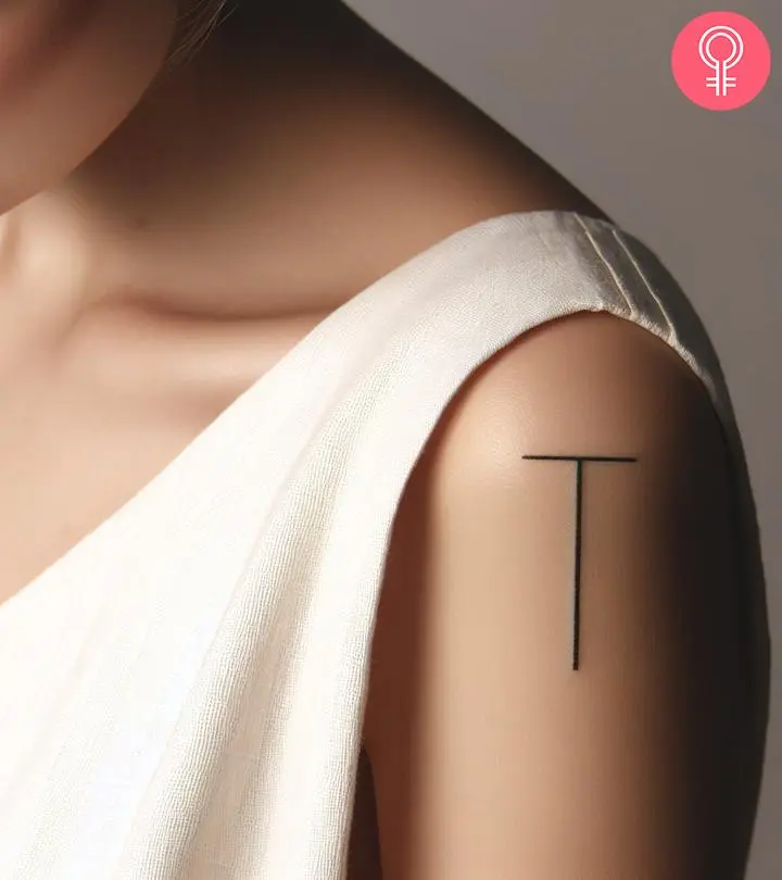 A woman wearing a ‘T’ style letter tattoo on the upper arm.