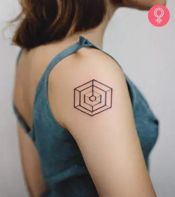 A fine line geometrical hexagon tattoo on the upper arm