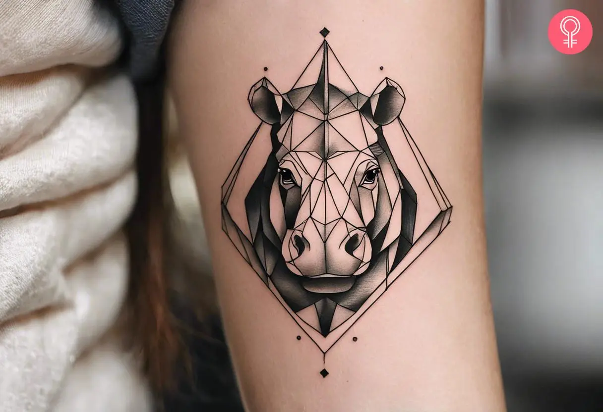 A geometric hippo tattoo on the upper arm of a woman