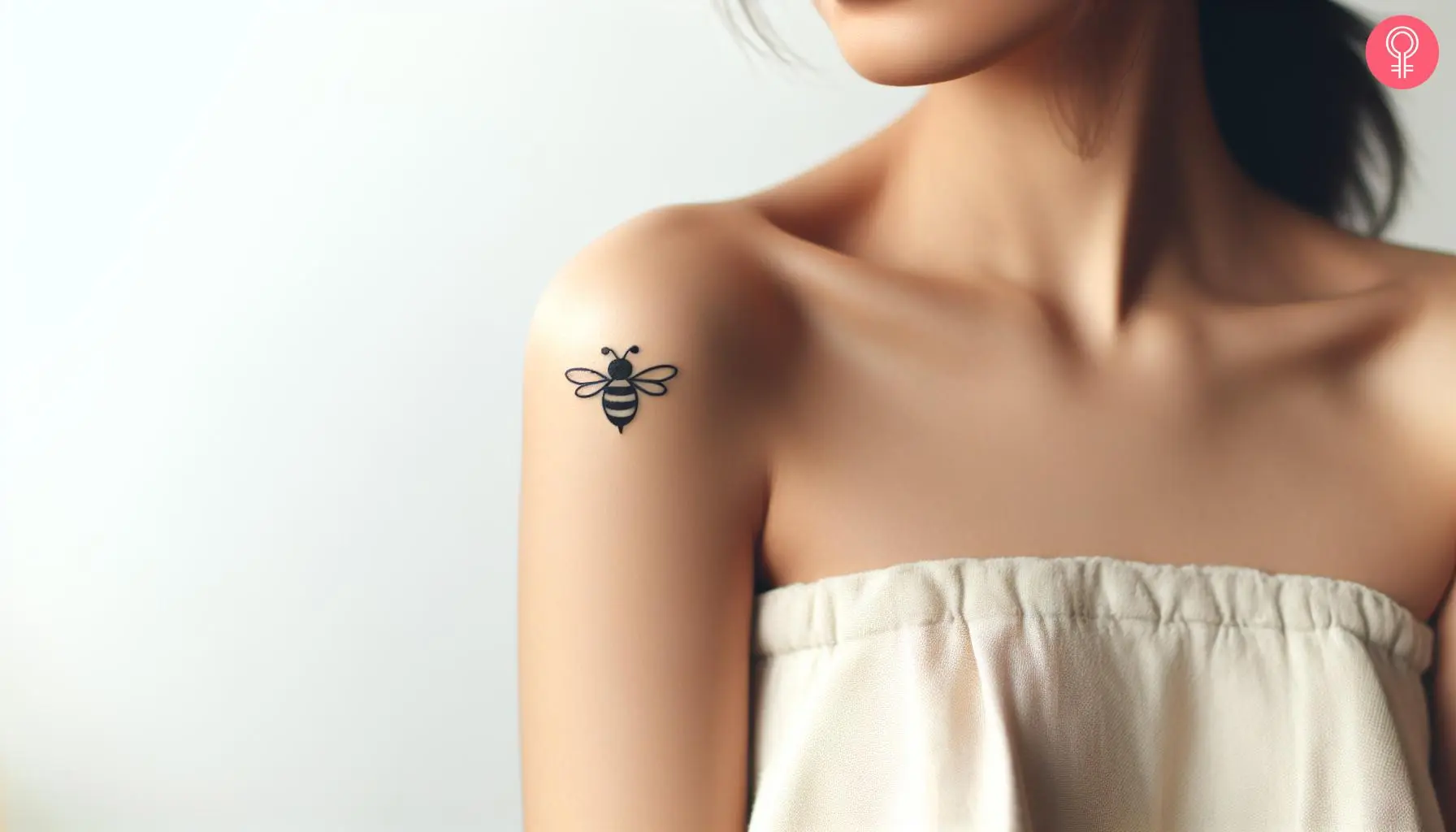 A minimal cartoon bee tattoo on the upper arm of a woman