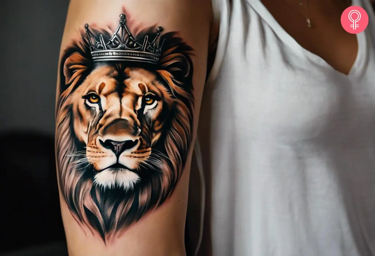 A realistic crowned lion head tattoo on the upper arm