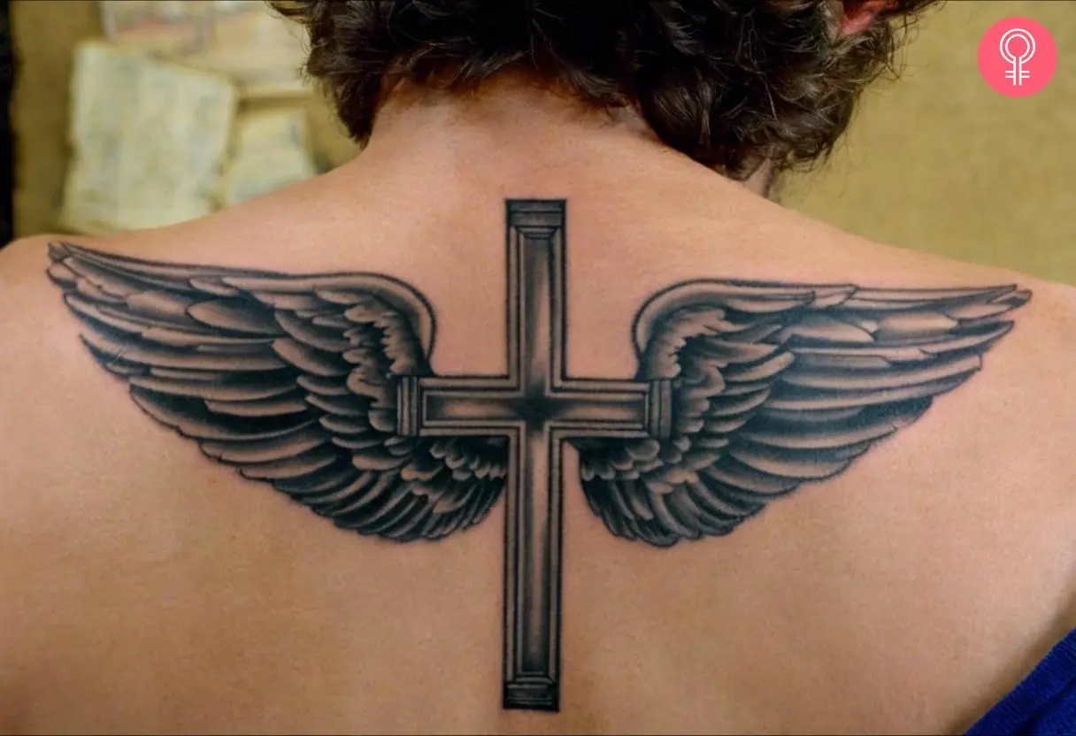 A traditional cross tattoo with wings inked on the back