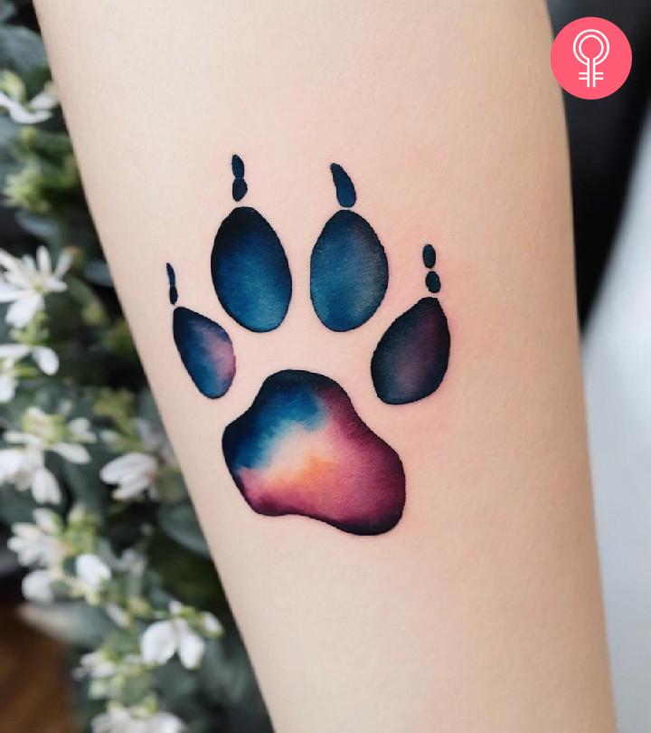 A watercolor paw tattoo on the forearm