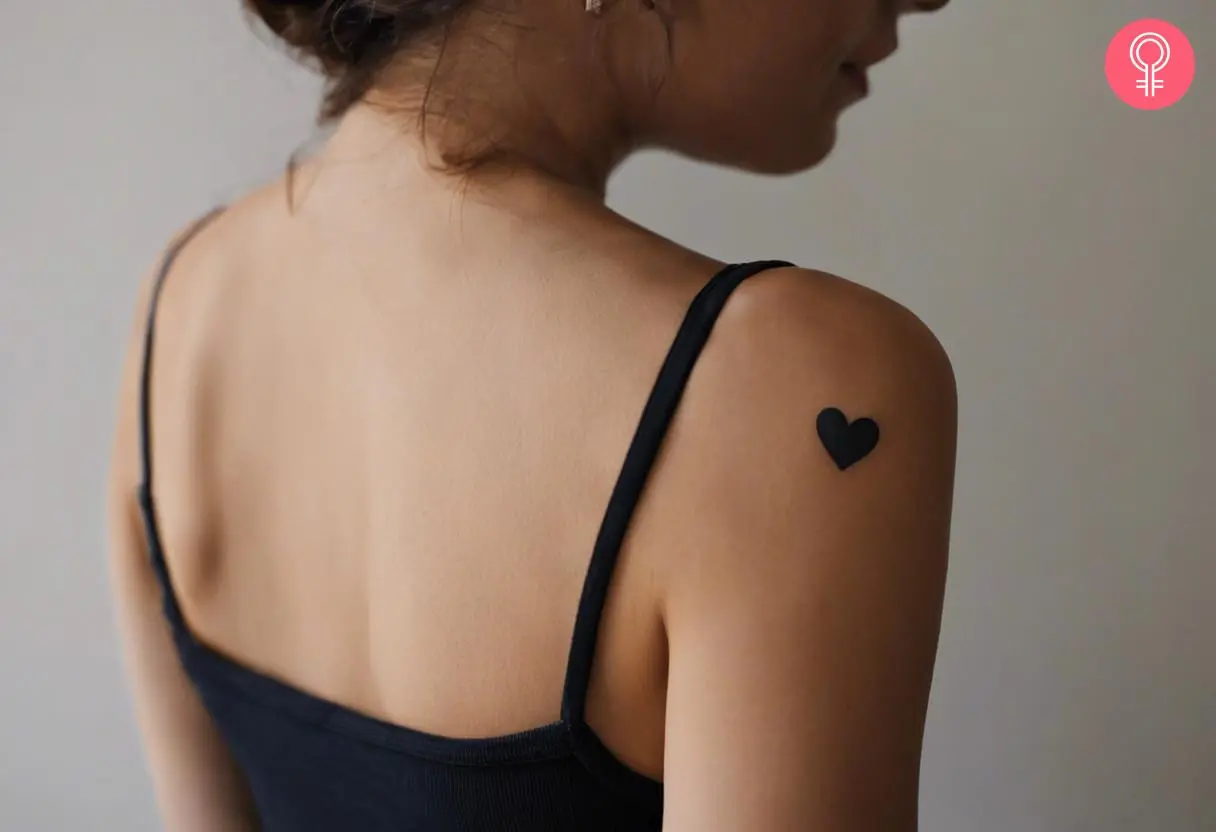 A woman wearing a small shoulder tattoo on the back.