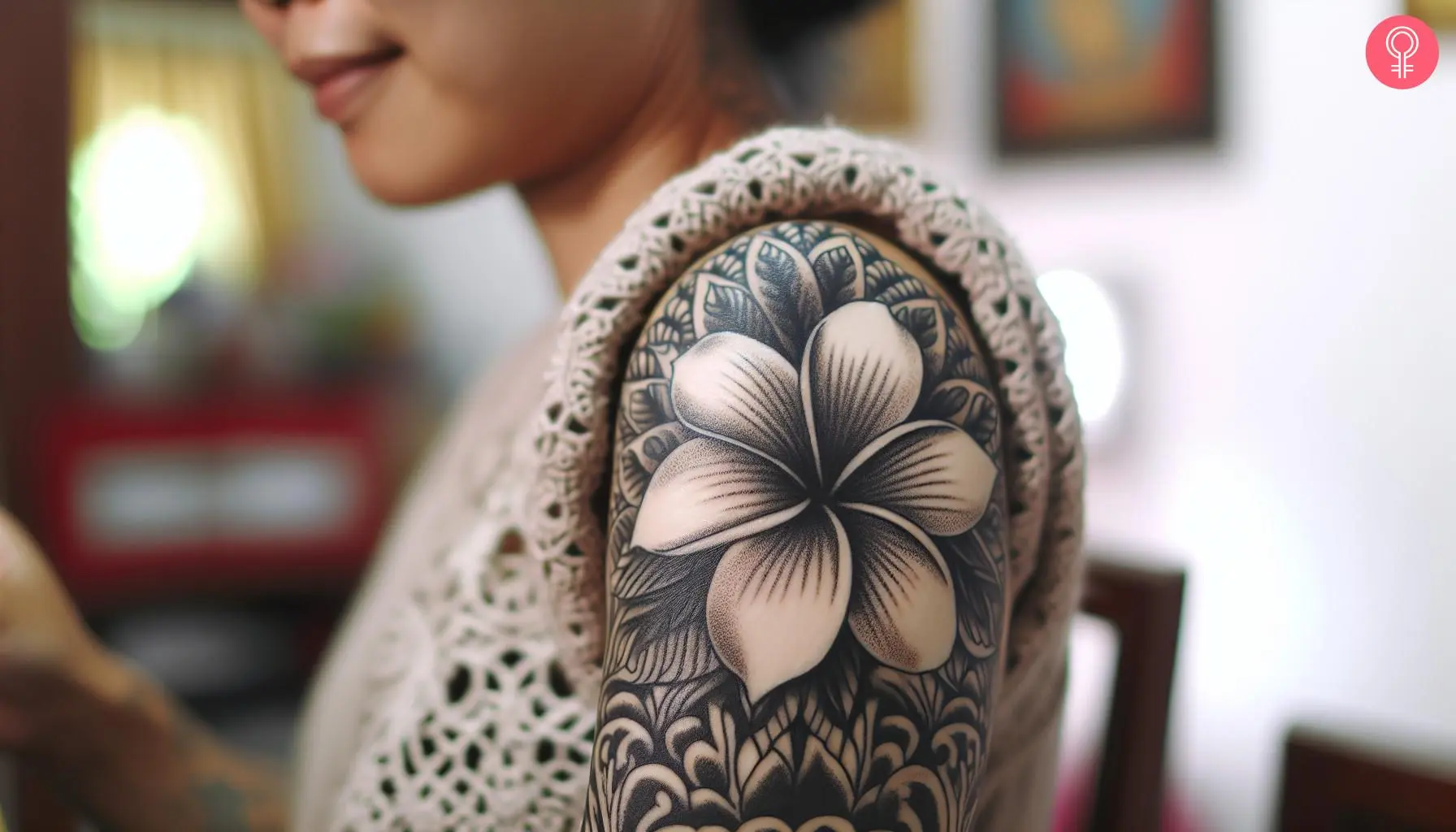 A woman with a black and white frangipani flower tattoo on her upper arm