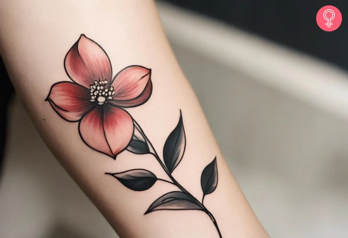 A woman with a minimalist dogwood flower tattoo on her forearm