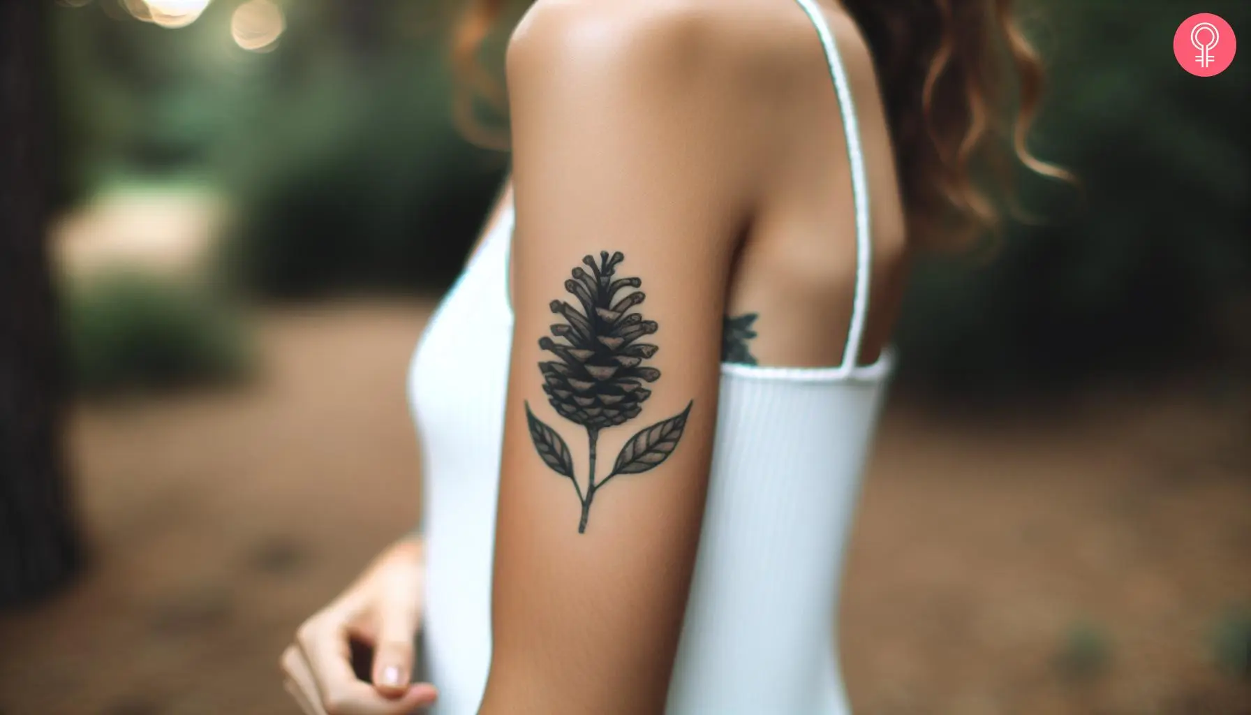 A woman with a minimalist tattoo of a pine cone with two leaves