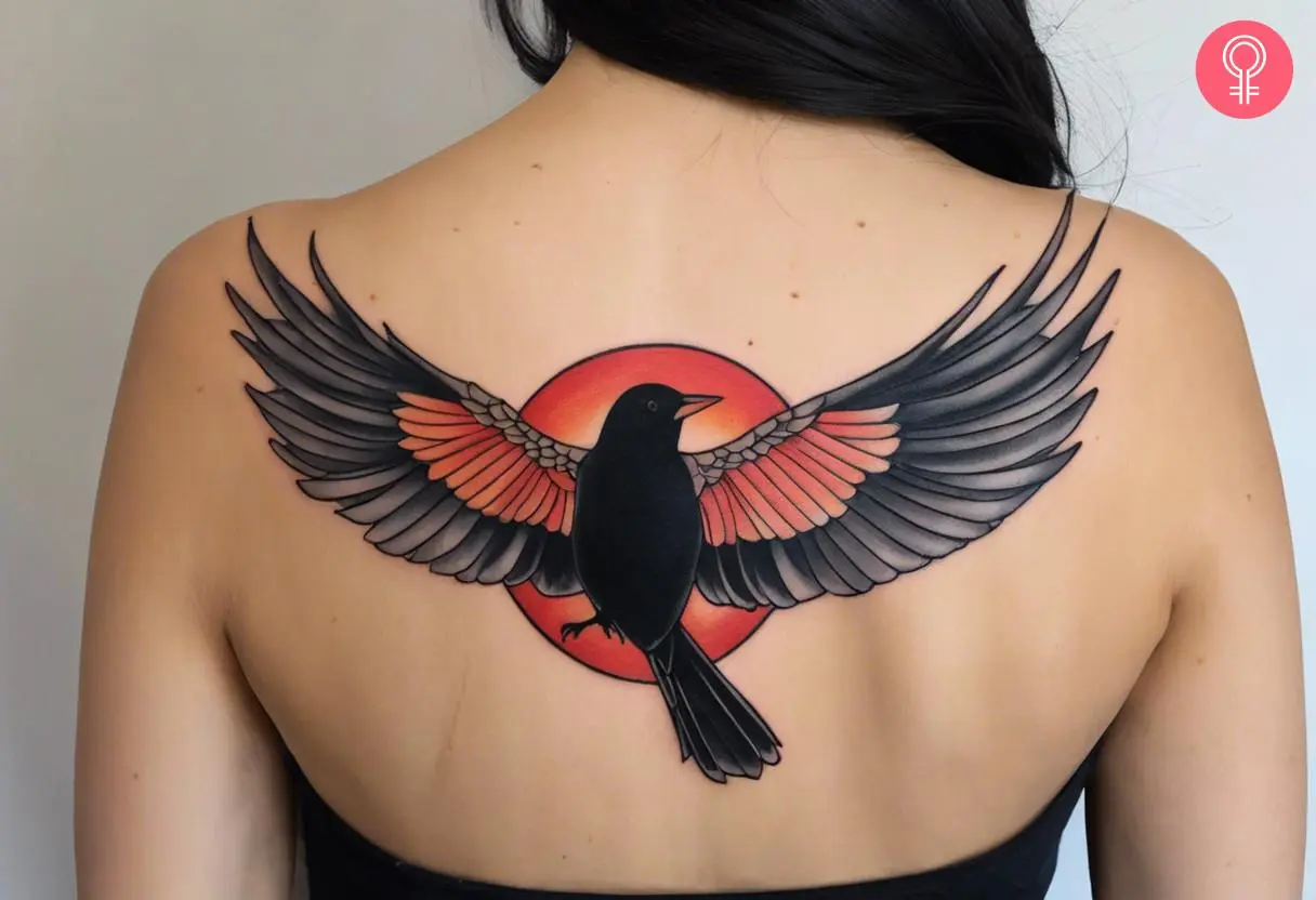 A woman with a red-winged blackbird tattoo on her back