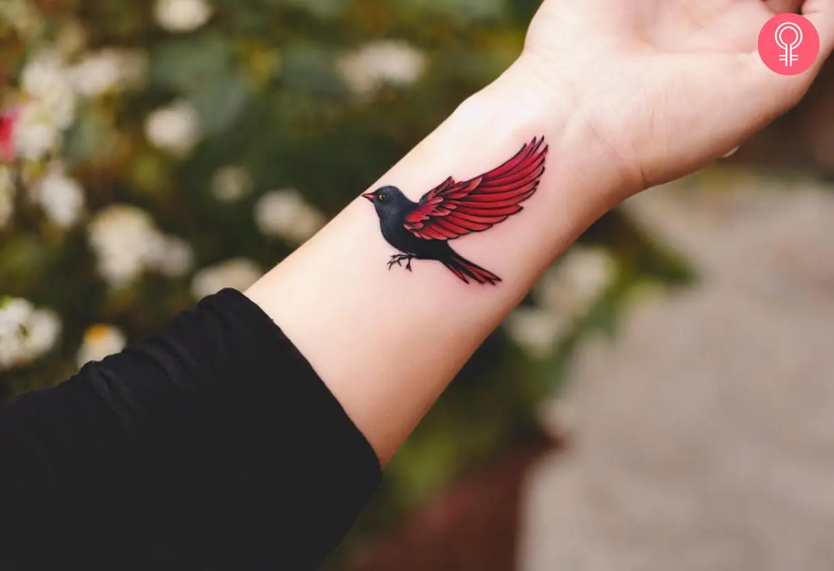 A woman with a small red-winged blackbird tattoo on her wrist