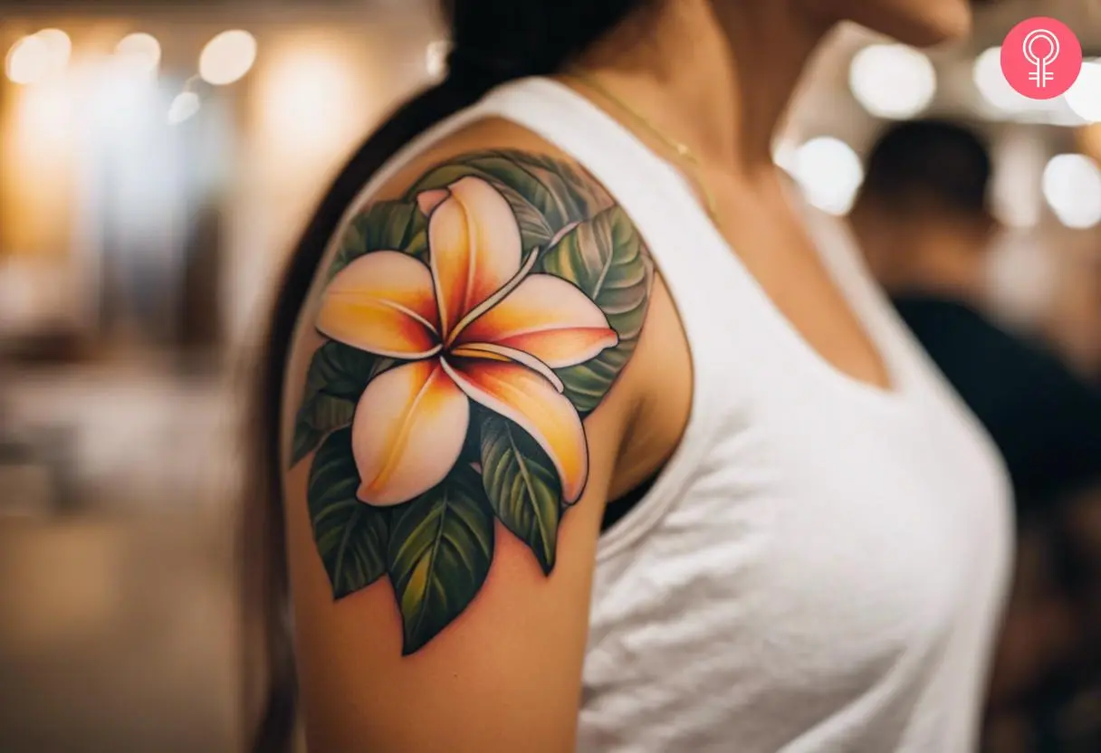 A woman with a vibrant frangipani flower tattoo on her upper arm