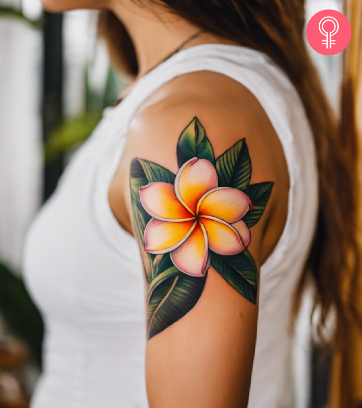 A woman with a vibrant frangipani flower tattoo on her upper arm