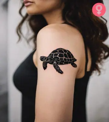 A woman with black tortoise tattoo on her upper arm