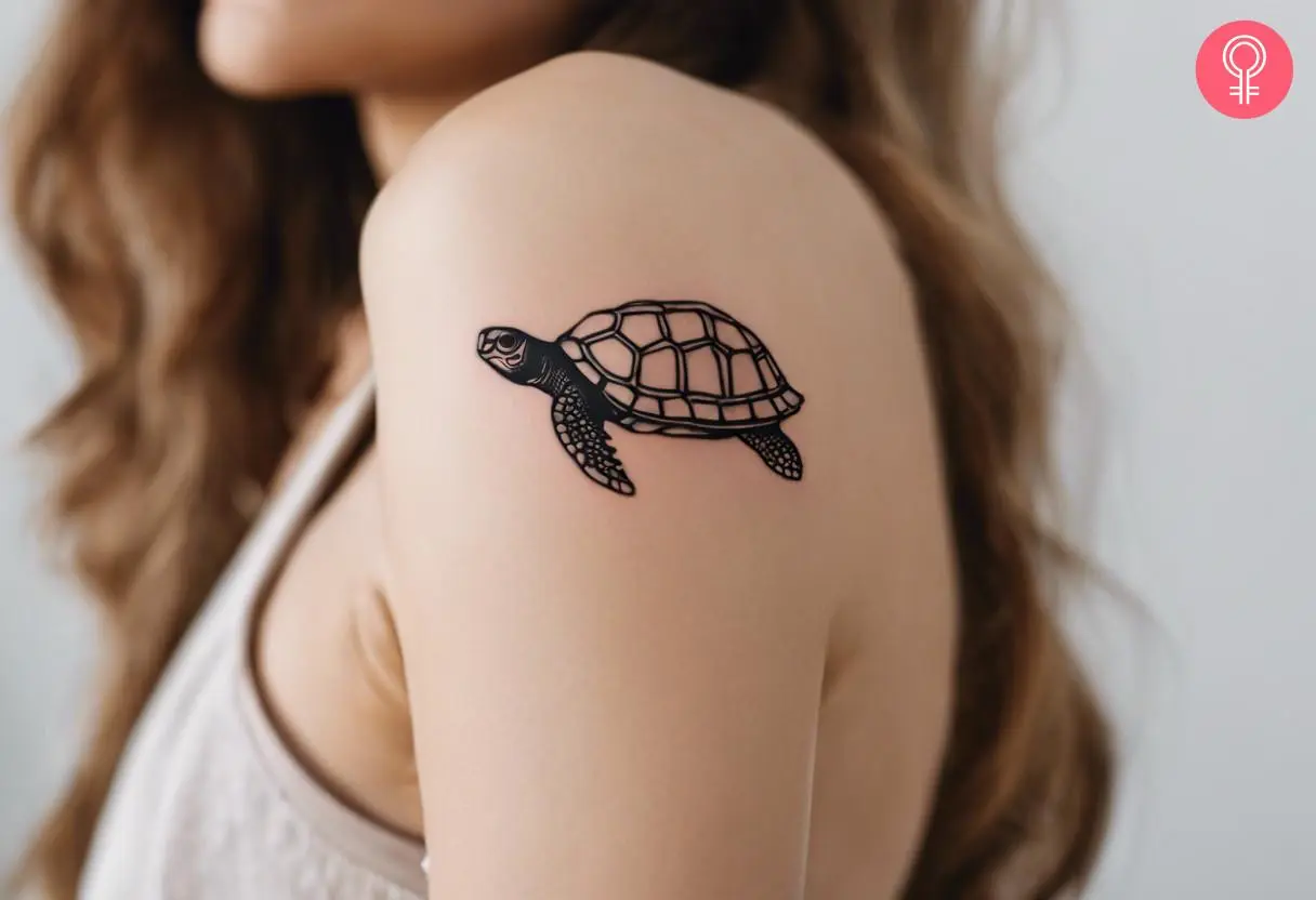 A woman with minimalist black tortoise tattoo on her upper arm