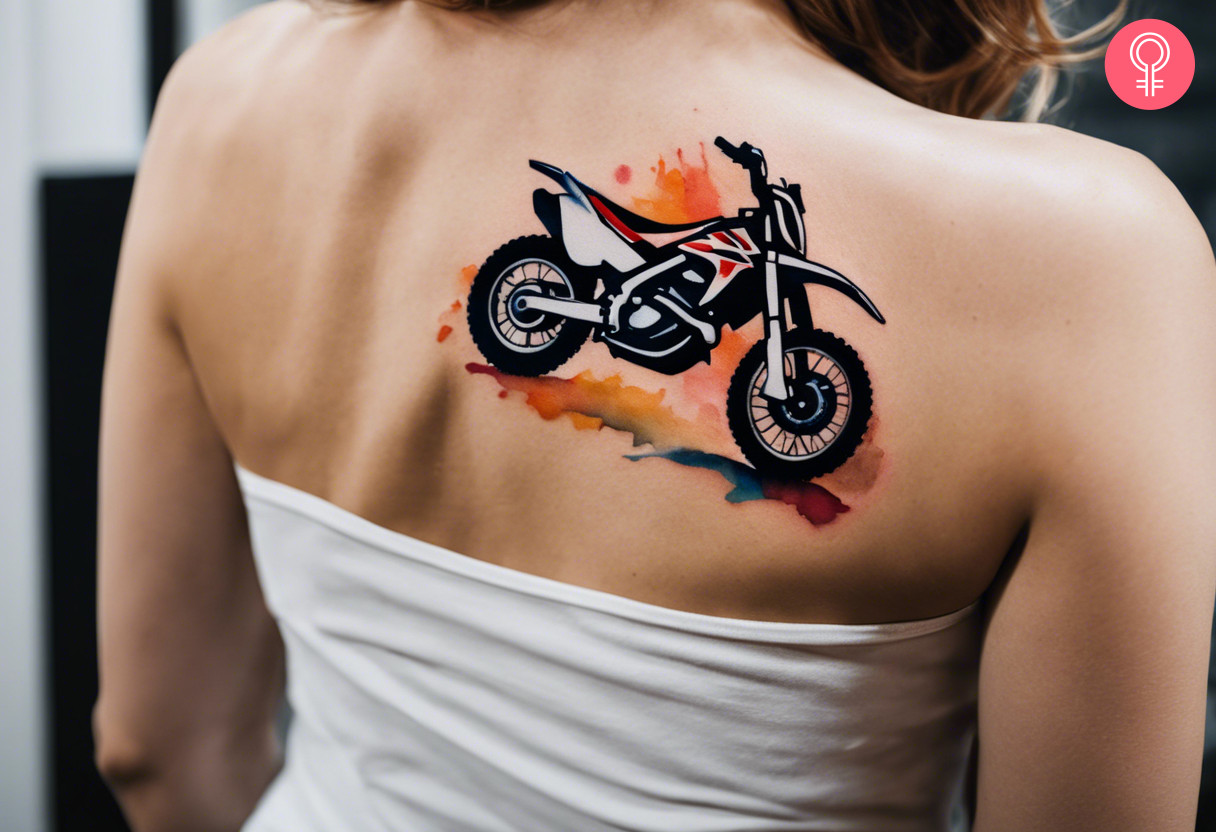 Woman with a colorful abstract minimalist dirt bike tattoo on the upper back