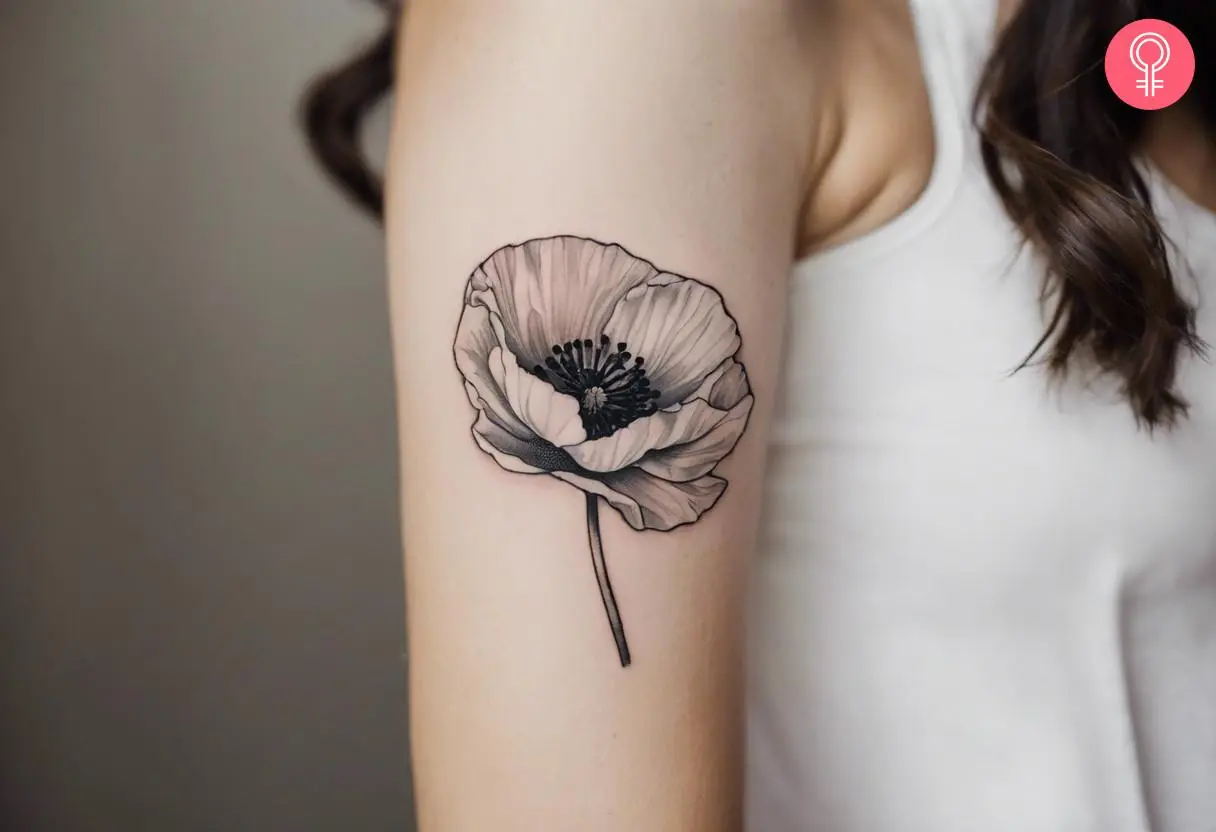 An August birth flower tattoo in black and white ink on a woman’s bicep