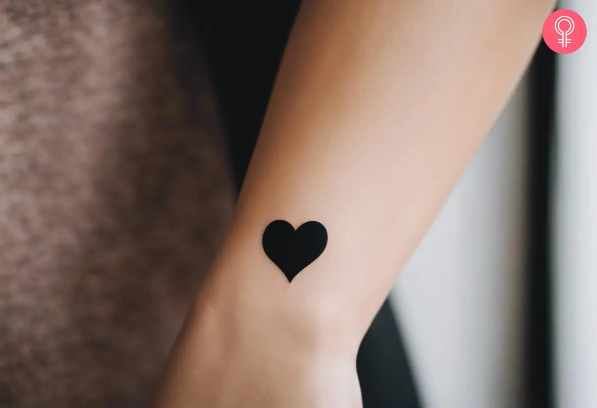 A woman with a black solid heart tattoo on her wrist