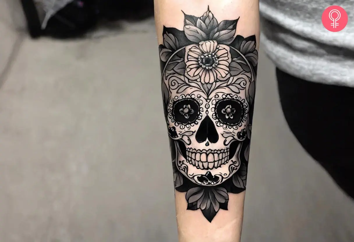 Black-and-grey sugar skull tattoo on a woman’s arm