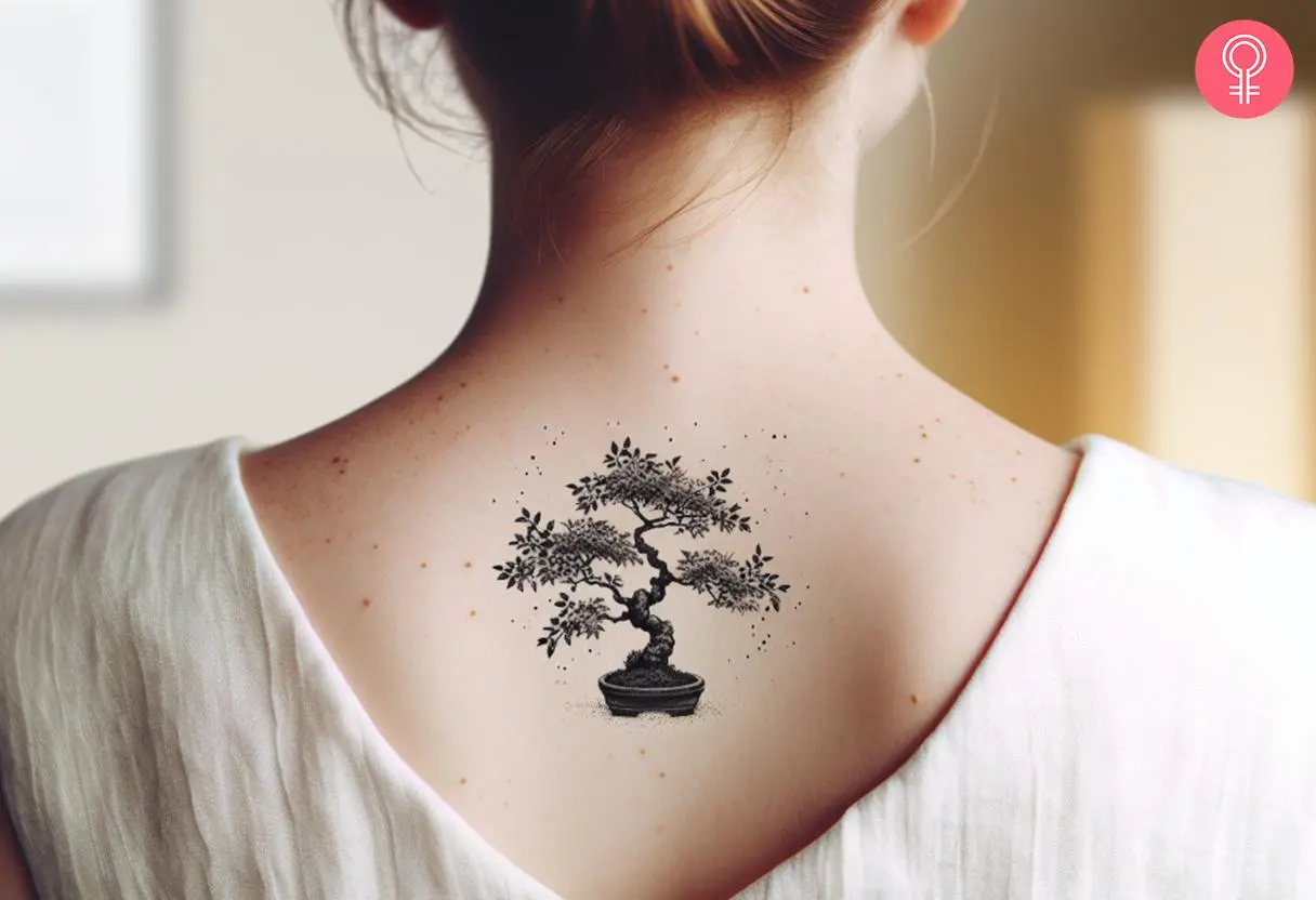 A woman with a black small bonsai tree tattoo on her upper back