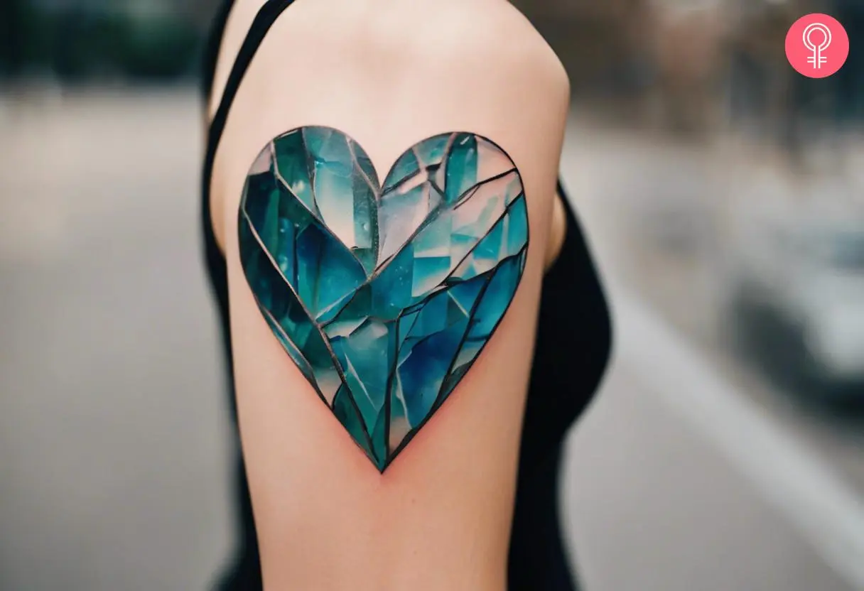 A woman with a colored broken glass heart tattoo on her upper arm