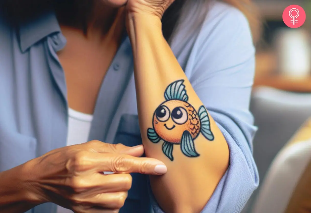 A cartoon goldfish tattoo on a woman’s arm