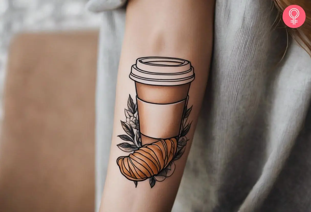 Woman with coffee and croissant tattoo on her forearm