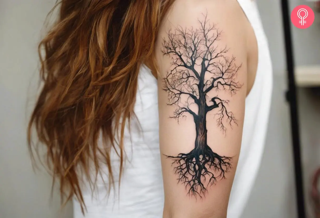 Dead tree with roots tattooed on a woman’s bicep