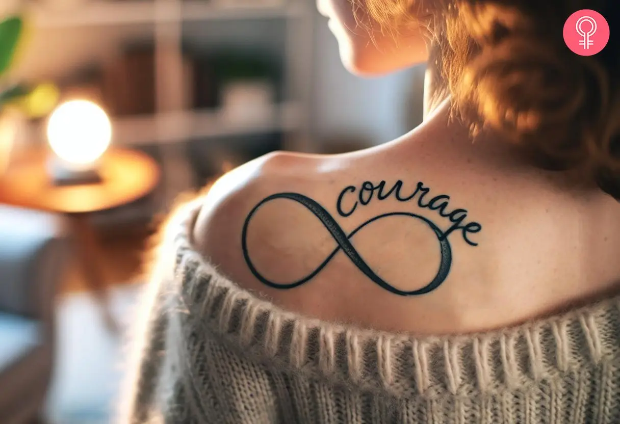 A courage script tattoo with an infinity sign on the back of the shoulder