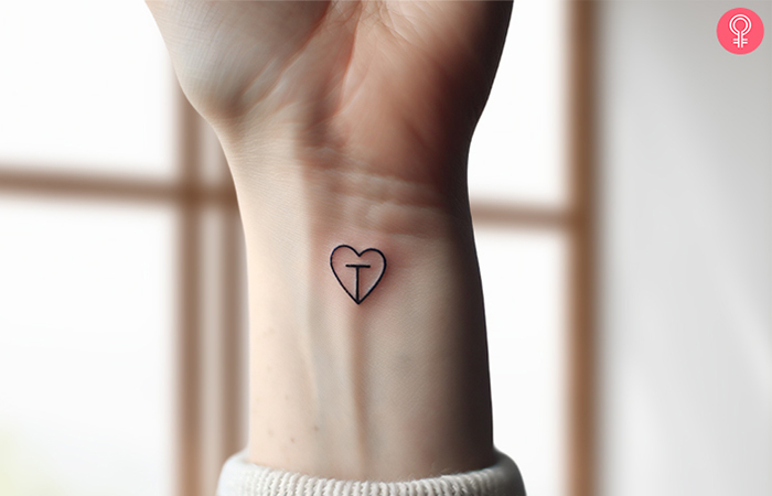 A woman wearing a fancy tattoo of ‘T’ letter placed inside a tiny heart on her wrist