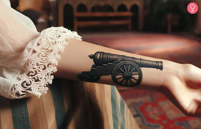 A woman with a black cannon tattoo on her forearm